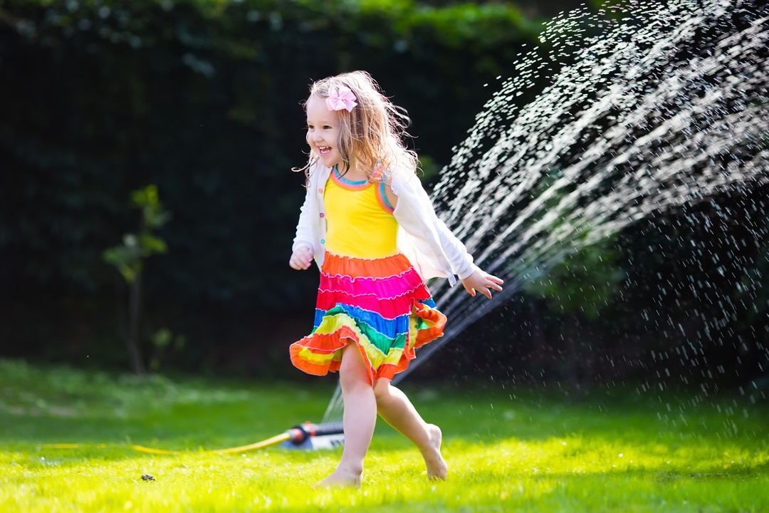 girl in sprinkler on lawn